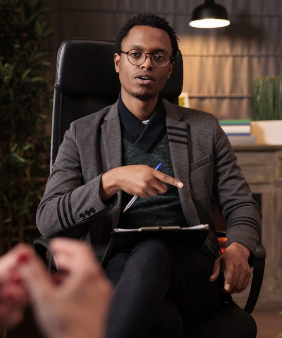 Male psychotherapist doing psychoanalysis consultation with couple at therapy session in office. Giving relationship advice to solve conflict between angry partners, counseling support.